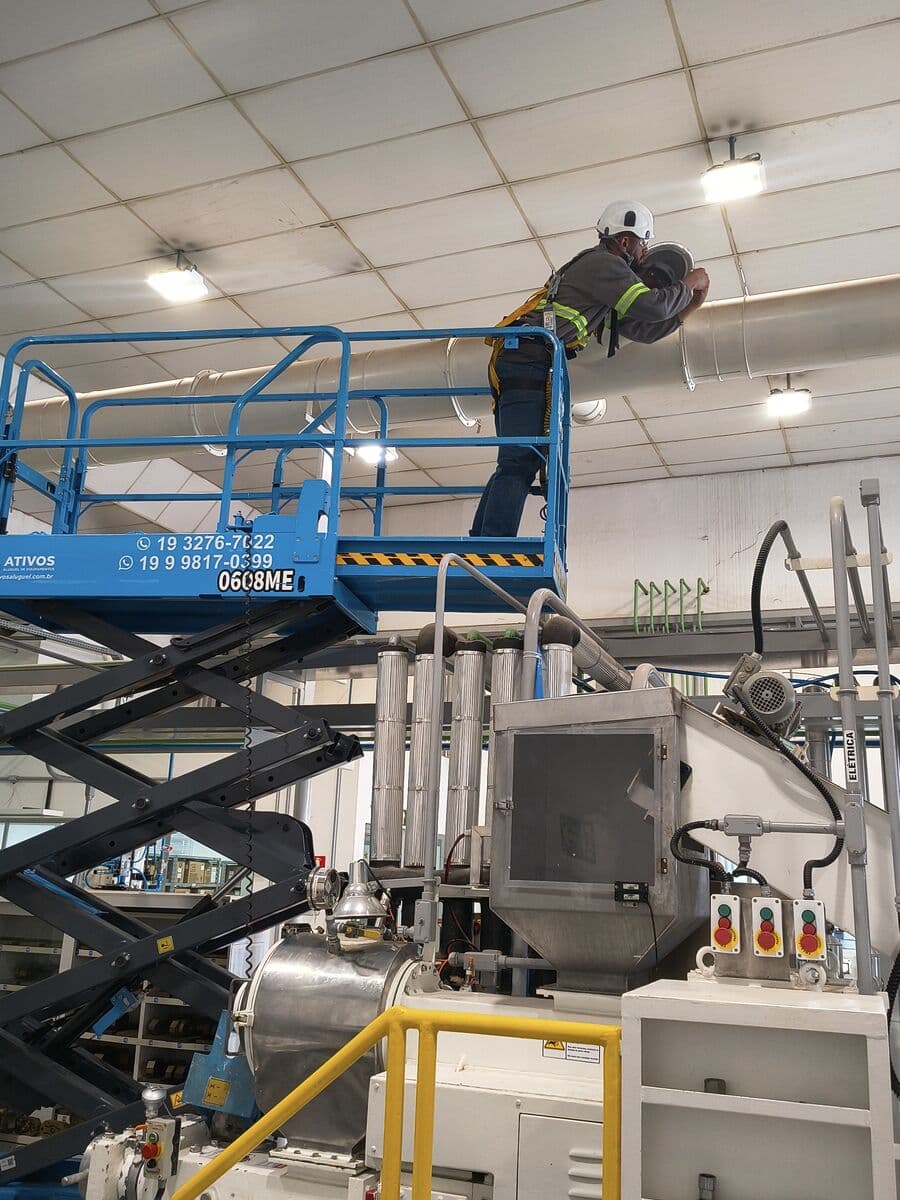 Montador em plataforma elevatória trabalhando em tubulação junto ao teto