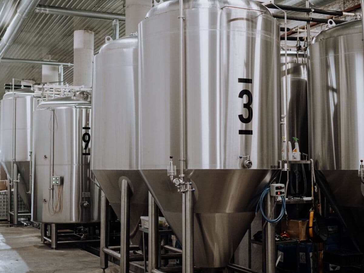 Tanques de processo em aço inox alinhados em fábrica de bebidas