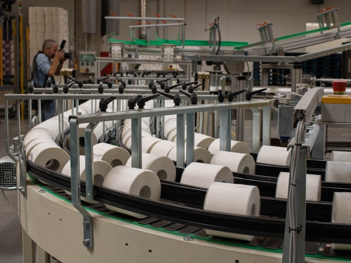 Rolos de papel higiênico correndo numa esteira transportadora de fábrica