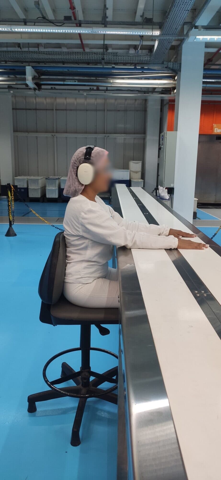 Operadora sentada num posto de packing manual ao lado de uma esteira de lona dupla