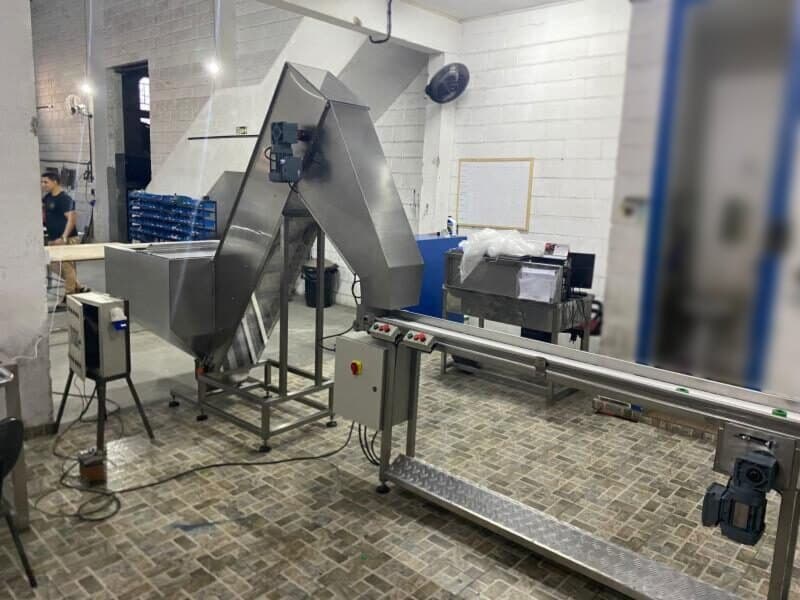 Silo em aço inox com elevador inclinado alimentando uma esteira, na oficina